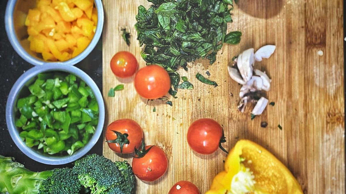 Tomatoes, bell pepper and broccoli on a wooden cutting board