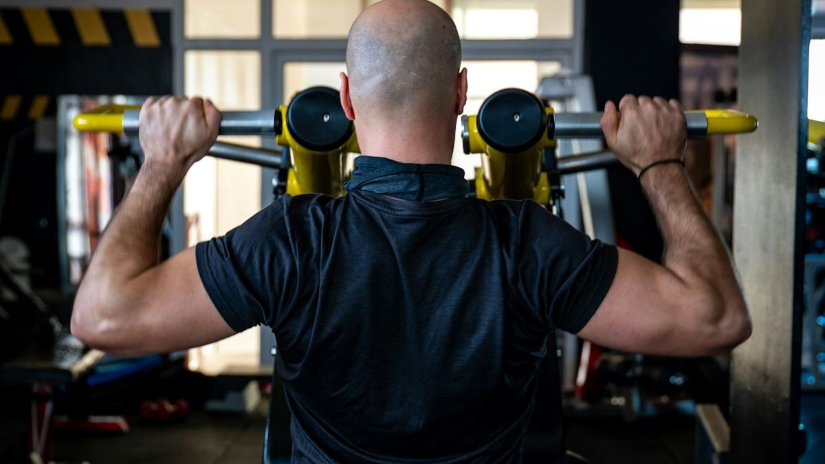 Man training on a shoulder press machine in a gym